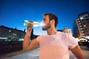 hombre bebiendo agua después de la sesión de carrera foto