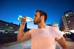 hombre bebiendo agua después de la sesión de carrera foto