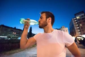 hombre bebiendo agua después de la sesión de carrera foto