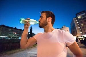 hombre bebiendo agua después de la sesión de carrera foto