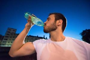 hombre bebiendo agua después de la sesión de carrera foto