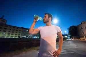 hombre bebiendo agua después de la sesión de carrera foto