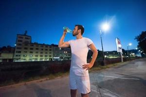 man drinking water after running session photo