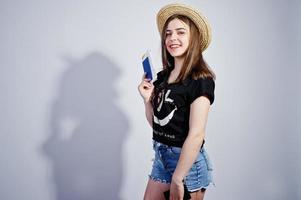 Girl tourist with passport, wear in lol shirt, shorts and hat isolated on white. photo