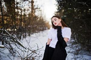 Fashionable long legs brunette model in long black cloak posed outdoor at winter day. photo