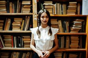 Girl with pigtails in white blouse at old library. photo