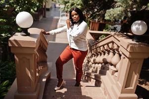 mujer de negocios afroamericana vestida formalmente con blusa blanca y pantalones rojos. exitosa empresaria de piel oscura. foto