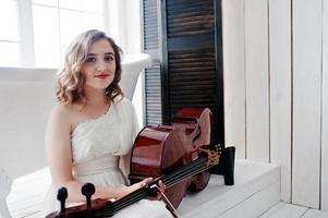 Pretty young gilrl musician in white dress with double bass. photo