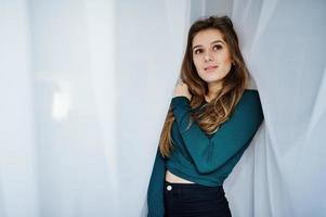 Handsome brunette girl wear on green, posing at curtains. Studio model portrait. photo