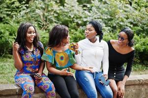 grupo de cuatro chicas afroamericanas sentadas al aire libre y divirtiéndose. foto