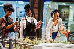 Group of african womans with shopping cart buying exotic fruits in grocery store supermarket. photo