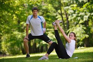 pareja haciendo ejercicio de estiramiento después de trotar foto