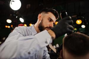 apuesto hombre barbudo en la barbería, peluquero en el trabajo. foto