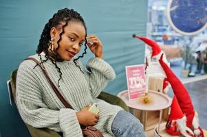 African woman posed in sweater and jeans posed at mall against christmas decoration and new year theme. photo