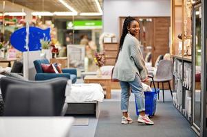 African woman walking with shopping basket in a modern home furnishings store. photo