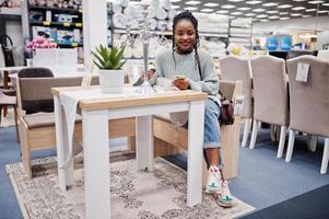 African woman choosing the right furniture for her apartment in a modern home furnishings store. photo