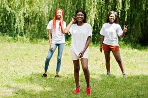 Three african american womans in park at white t-shirts. photo