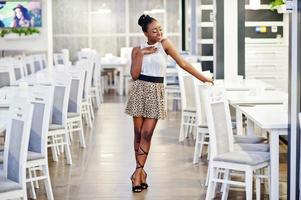 encantadora mujer afroamericana con falda de leopardo posando en el restaurante. foto