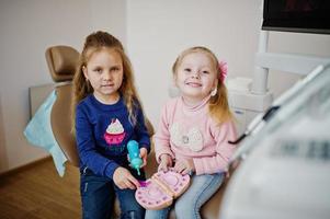 Two cutie little baby girls at dentist chair. Children dental. photo