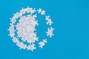 White jigsaw puzzle pieces on a blue background. Problem solving concepts. Texture photo with copy space for text