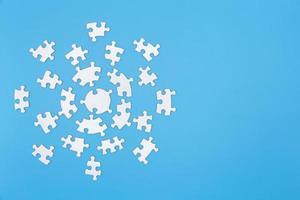 Unfinished white jigsaw puzzle pieces on blue background,  Copy space. photo