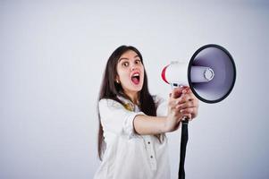 Portrait of a young woman in blue trousers and white blouse posing with megaphone in the studio. photo