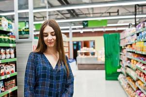 Shopping woman looking at the shelves in the supermarket.  Portrait of a young girl in a market store. photo