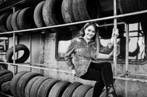 Young hipster girl in jeans jacket and head scarf at tire fitting zone. photo