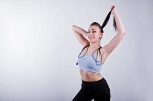 Cheerful attractive young fitness woman in top and black leggings with jump rope isolated over white background. photo
