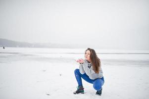 Funny girl wear on hoody sweater and jeans, at frozen lake in winter day. photo