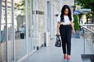 elegante mujer de negocios afroamericana con bolso en las calles de la ciudad. foto