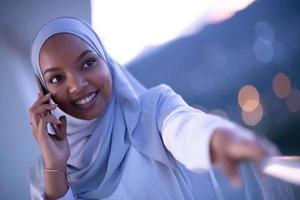 Young Muslim woman on  street at night using phone photo