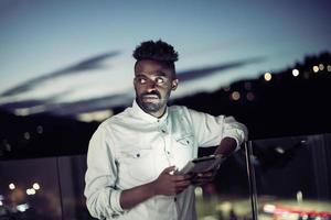 joven afro en la calle por la noche usando el teléfono foto