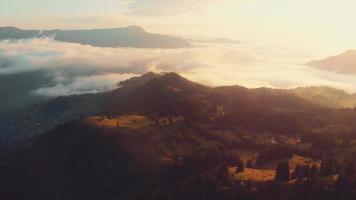 Luftfliegen über der malerischen Herbstwaldlandschaft über Wolken und Nebel an dunstigen Abenden mit Sonne über dem Horizont. majestätische georgia kaukasus drohnenlandschaft video