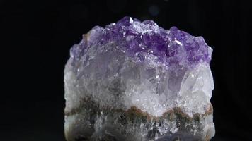 Amethyst aus nächster Nähe. Nahaufnahme eines Amethystfelsens, der sich im dunklen Hintergrund dreht. video