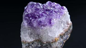 Amethyst aus nächster Nähe. Nahaufnahme eines Amethystfelsens, der sich im dunklen Hintergrund dreht. video