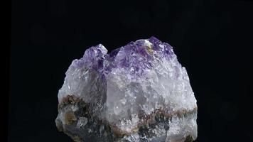 Amethyst aus nächster Nähe. Nahaufnahme eines Amethystfelsens, der sich im dunklen Hintergrund dreht. video