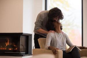 multiethnic couple hugging in front of fireplace