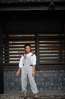 African american woman in overalls and beret posed outdoor against wooden background. photo