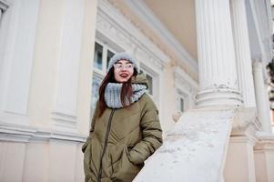 Portrait of brunette girl in gray scarf and hat, glasses at cold weather. photo