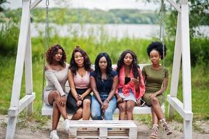 Group of five african american girls relaxing at beautiful swing. photo