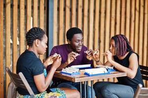 Group of three african american friends play table games. photo