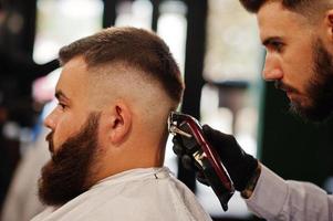 apuesto hombre barbudo en la barbería, peluquero en el trabajo. foto