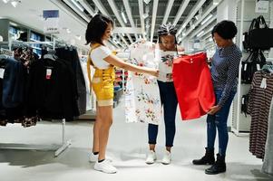 tres mujeres africanas eligiendo ropa en la tienda. dia de compras. foto
