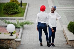 dos jóvenes musulmanas africanas modernas, atractivas, altas y delgadas con hiyab o turbante en la cabeza posaron juntas. foto