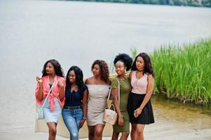 Group of five african american girls standing at sand against lake. photo