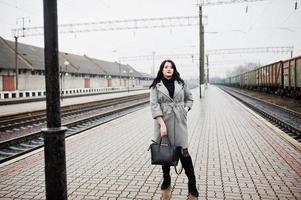 Brunette girl in gray coat posed in railway station. photo