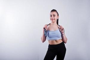 Cheerful attractive young fitness woman in top and black leggings with jump rope isolated over white background. photo