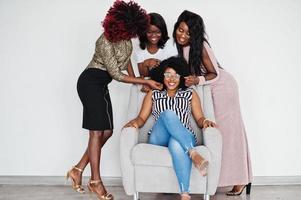 Happy brightful positive moments of four african girls. Having fun and smiling on chair against white empty wall. Lovely moments of four best friends. photo