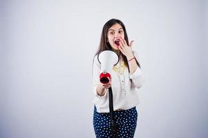 Portrait of a young woman in blue trousers and white blouse posing with megaphone in the studio. photo